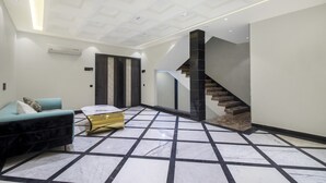 A modern interior with a marble floor, a sofa, a gold accent piece, and a staircase. - Treebo Taj Dream Agra (Agra)