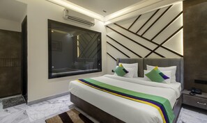 A modern bedroom with a large bed, a built-in air conditioning unit, a bedside table with a phone, and a wall-mounted mirror. - Treebo Taj Dream Agra (Agra)
