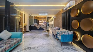 A modern hotel lobby with a marble floor, a sofa, a coffee table, and a reception desk. - Treebo Taj Dream Agra (Agra)