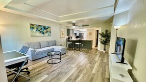 A modern living room with a grey sectional sofa, a glass coffee table, and a dining area with a kitchen in the background. - ++PRIME LOCATION++ Cozy Condo in Tucson Catalina Foothills Area (Tucson)