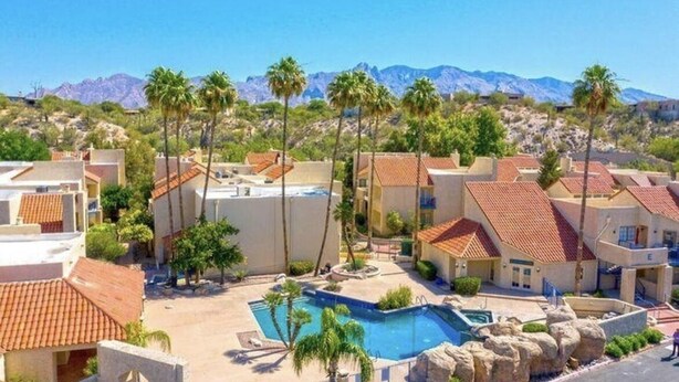 A residential area with a swimming pool surrounded by palm trees and houses with red-tiled roofs. - ++PRIME LOCATION++ Cozy Condo in Tucson Catalina Foothills Area (Tucson)