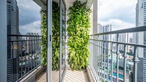A balcony with a glass railing, a potted plant, and a city view. - The Celavie Serviced Apartment Landmark (Ho Chi Minh City)