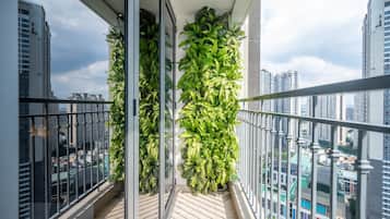 A balcony with a glass railing, a potted plant, and a city view.