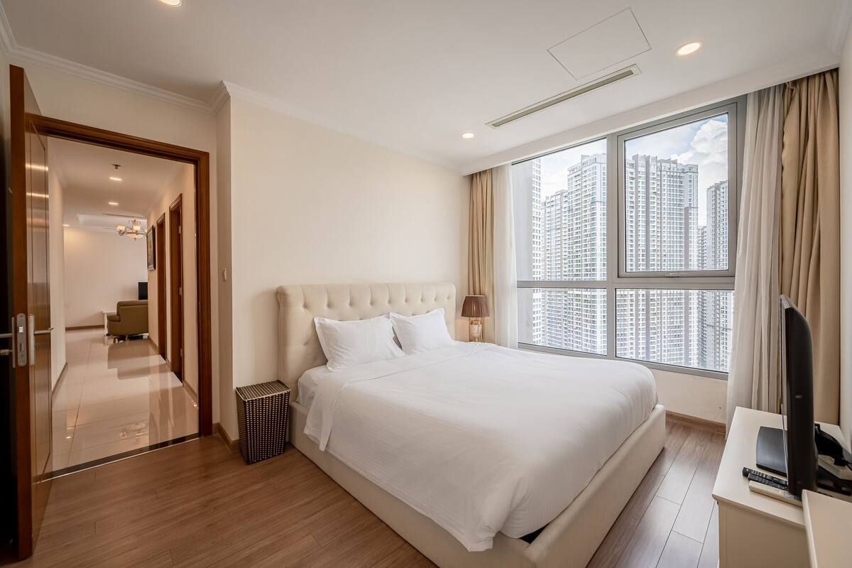Ein modernes Hotelzimmer mit einem großen Bett, einem Fernseher und Blick auf hohe Gebäude.