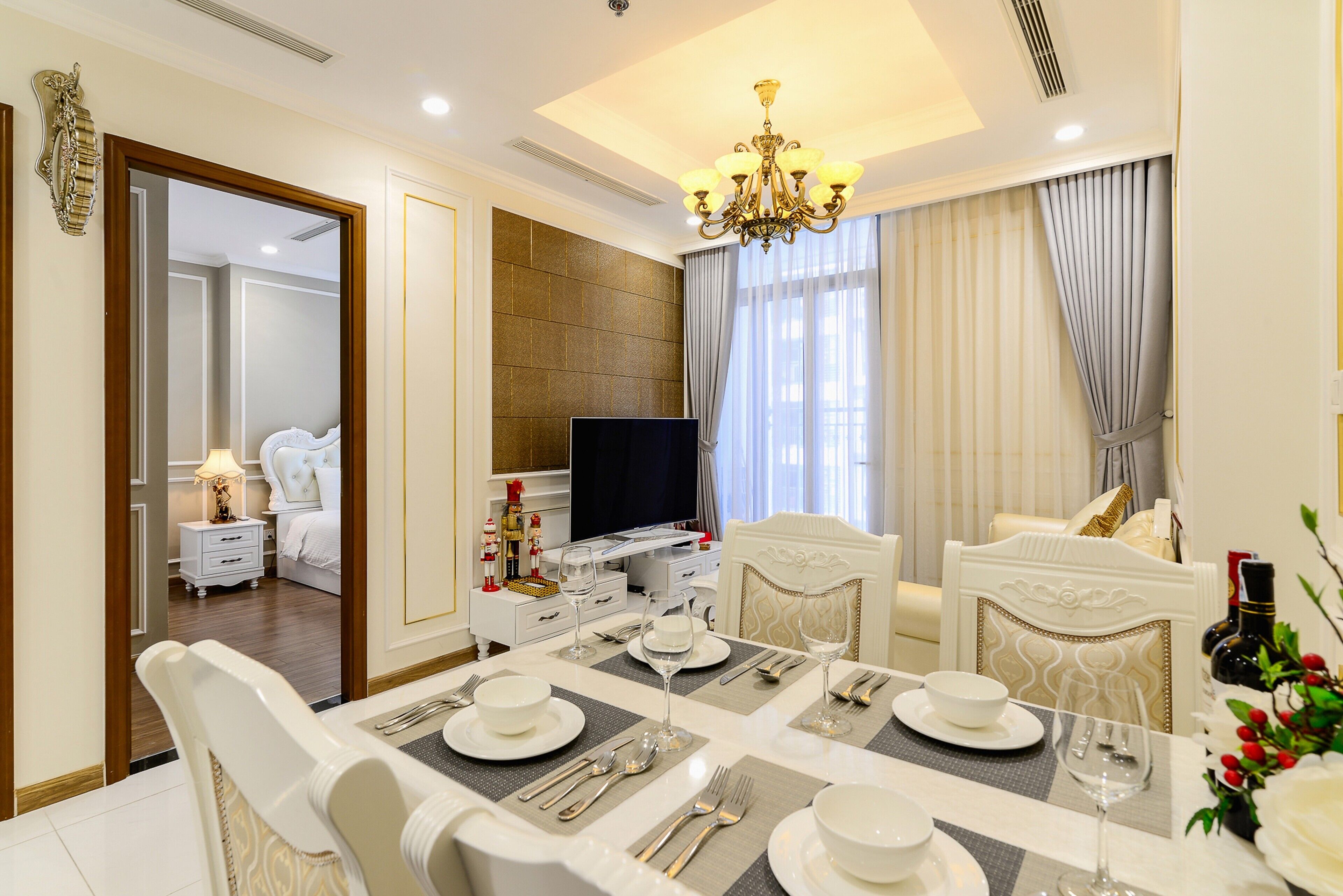 A hotel room with a dining area set for a meal, a television, and a bed with a nightstand.