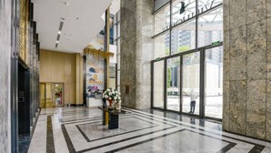 A spacious lobby with marble flooring, a large glass entrance, and a prominent 'AMARK' sign. - The Celavie Serviced Apartment Landmark (Ho Chi Minh City)