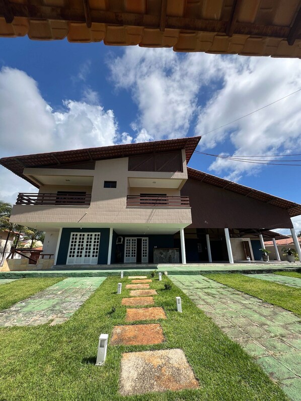 Una casa de dos pisos con techo plano y porche cubierto.
