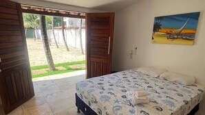 A bedroom with a bed, a painting, and a view of a garden. - Pousada Summer Kite Cumbuco (Caucaia)