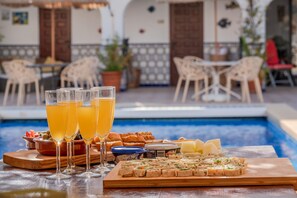 A poolside dining setup with glasses of orange juice, a variety of cheeses, and a tray of appetizers. - Casa Lola Callosa 10 - Callosa d'En Sarria, Costa Blanca (Callosa d'En Sarria)
