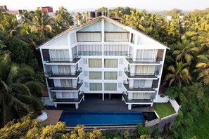 Un hotel de varios pisos con balcones, piscina y rodeado de exuberante vegetación.