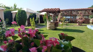 A garden with a gazebo, a stone fountain, and a variety of plants. - Sharkov Family Hotel  (Garmen)