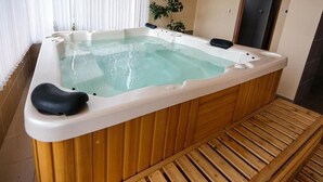 A hot tub with a wooden bench, a wooden floor, and a plant in the background. - Sharkov Family Hotel  (Garmen)