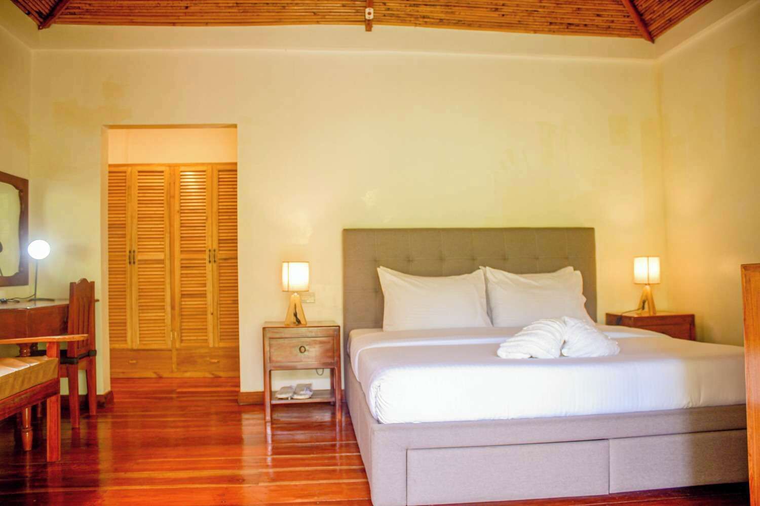 A hotel room with a bed, two bedside tables, a wooden desk, and a mirror.