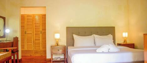 A hotel room with a bed, two bedside tables, a wooden desk, and a mirror.