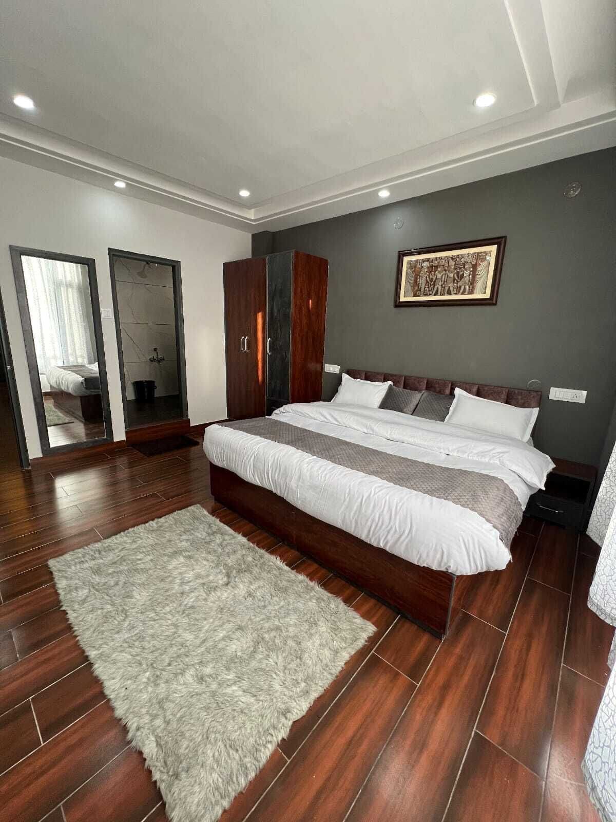 A modern bedroom with a large bed, wooden flooring, a fluffy rug, and a wardrobe.