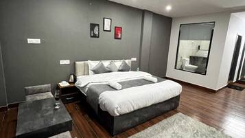 A modern bedroom with a large bed, a bedside table, a chair, and a small table with a glass of water.