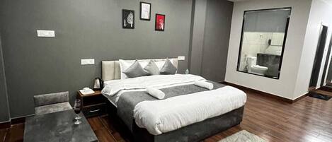 Un dormitorio moderno con una cama grande, una mesita de noche, una silla y una pequeña mesa con un vaso de agua.