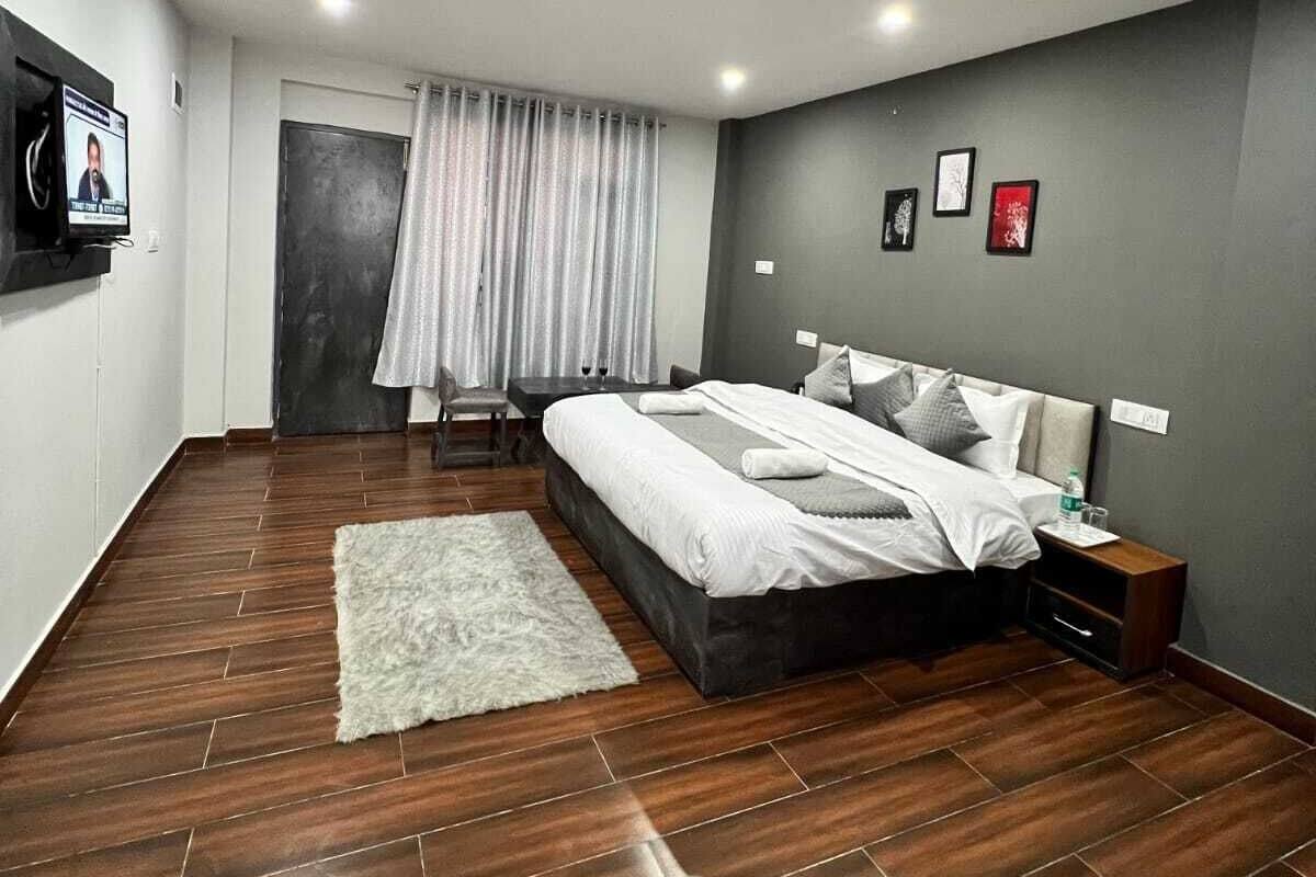 Un dormitorio moderno con una cama grande, un televisor de pantalla plana montado en la pared, una mesita y una silla.