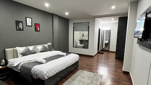 A modern bedroom with a large bed, a desk, and a TV. - The Getaway BNB (Shimla)
