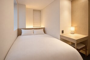Une chambre d’hôtel avec un lit, un bureau et une table de chevet avec une lampe.