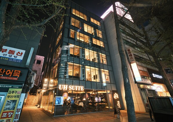 A modern building with a glass facade and a sign for 'UH SUITE' at the ground level. - UH Suite Seoul Deoksugung (Seoul)