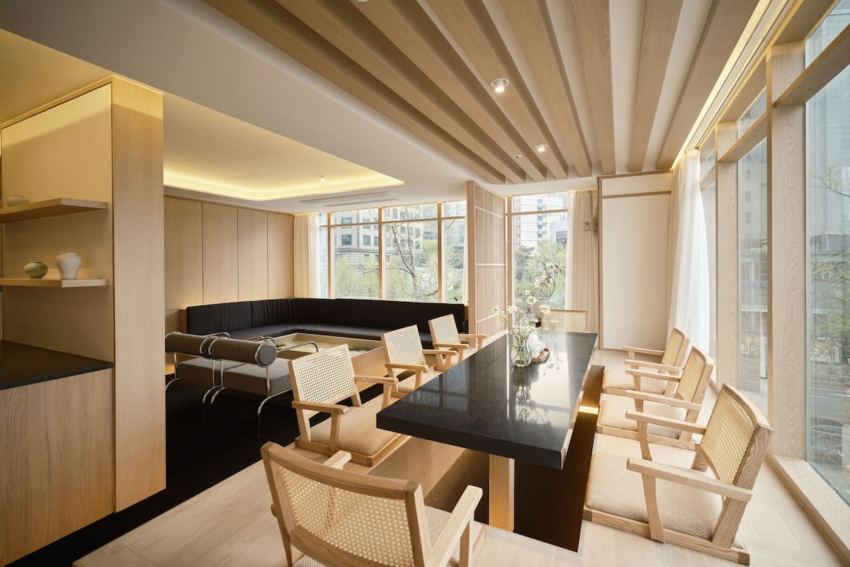 Een moderne keuken met een zwart aanrecht, houten stoelen en een grote eettafel.