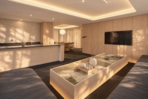 Un intérieur moderne avec une table centrale, un coin salon et un téléviseur fixé au mur.