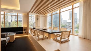 Uma sala de estar moderna com uma grande janela, um sofá, uma mesa de centro e uma área de refeições com cadeiras.