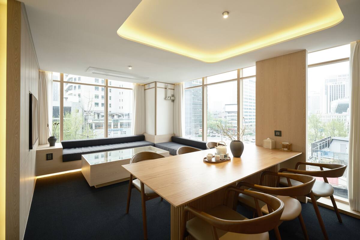 Een moderne vergaderruimte met een grote tafel, stoelen, een bank en uitzicht op de stad door grote ramen.