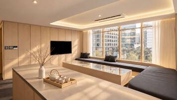 Quarto de hotel moderno com uma janela grande, televisão de tela plana, área de estar e bancada com serviço de chá.