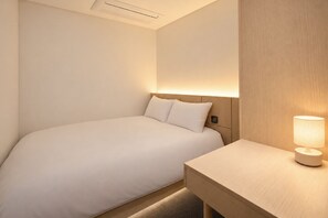Une chambre d’hôtel avec un lit, une table de chevet et une lampe.