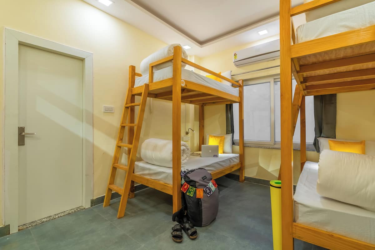 A bunk bed room with a ladder, a desk with a laptop, and a backpack on the floor.