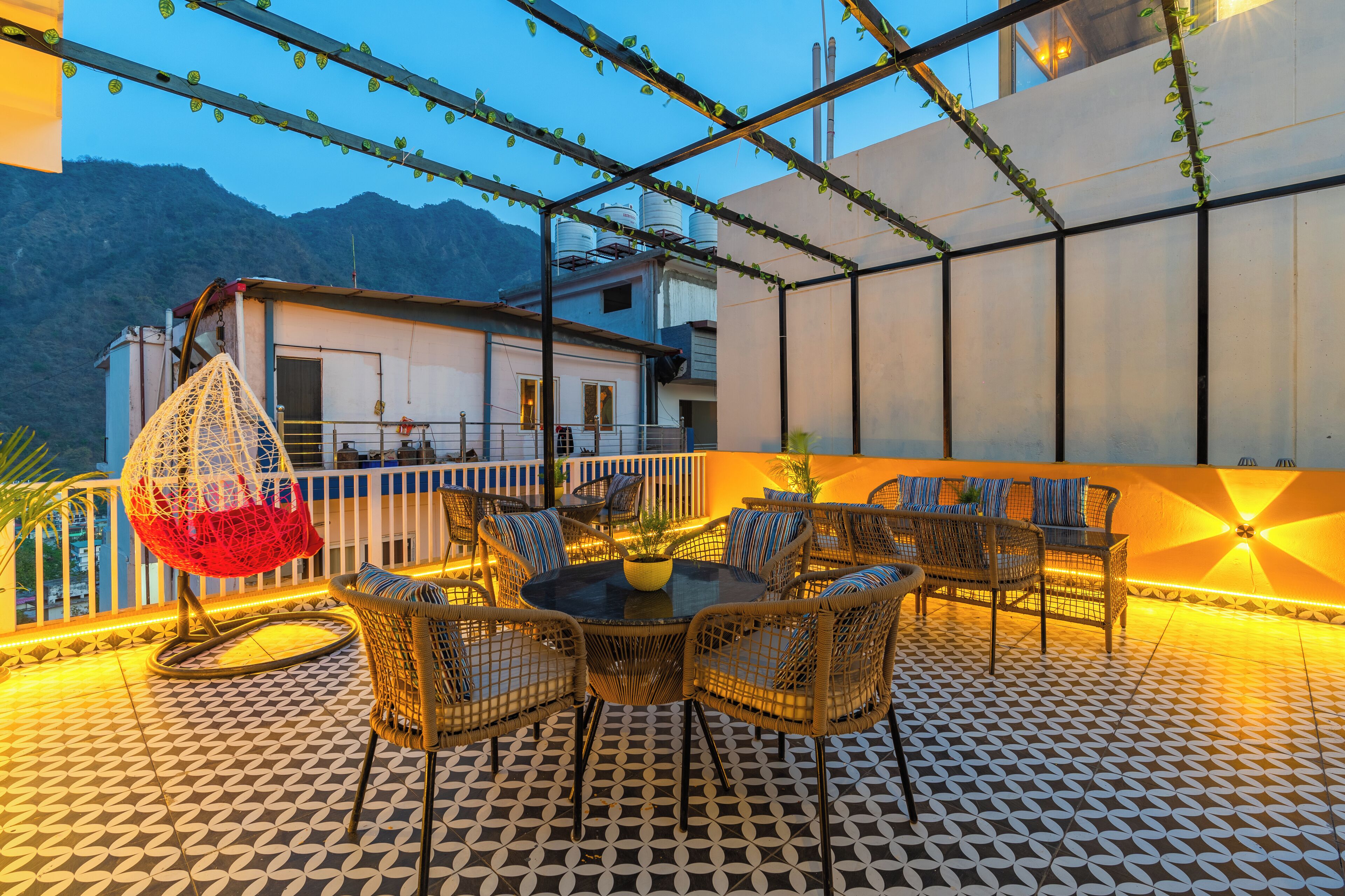 An outdoor patio with wicker furniture, a hanging chair, and a patterned floor.