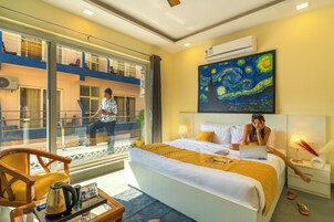 Habitación de hotel con cama, escritorio, silla, ventana y un cuadro en la pared.