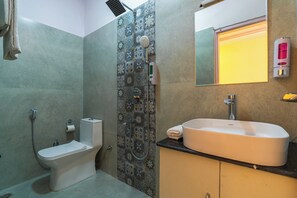 A bathroom with a toilet, a shower with a rain showerhead, a sink with a mirror above it, and a towel hanging on the wall.