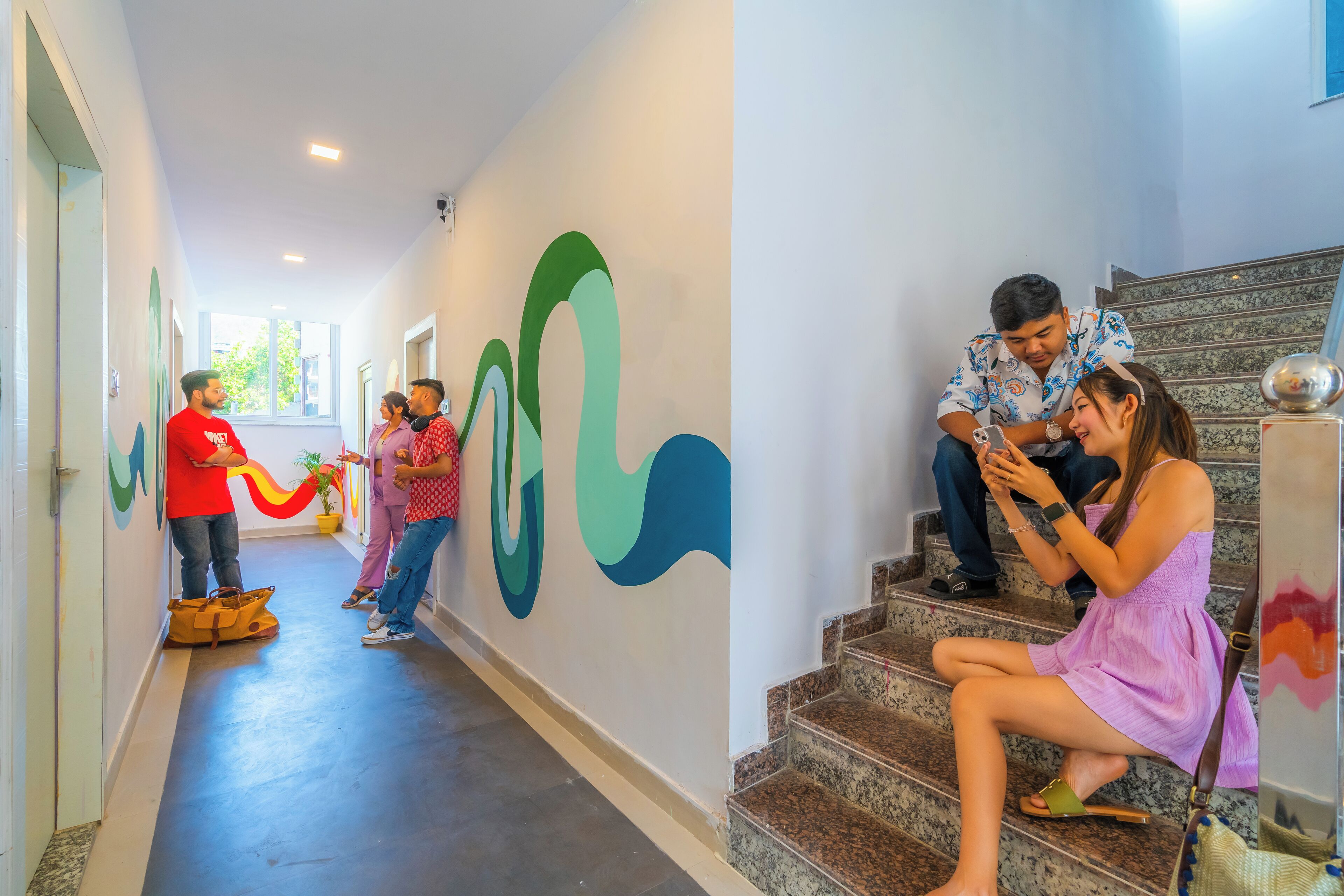 A hotel corridor with a modern design, including a staircase and a wall with abstract art.