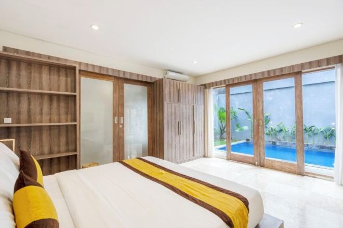 Un dormitorio con una cama grande, un armario y un ventanal corredero que da a una piscina.
