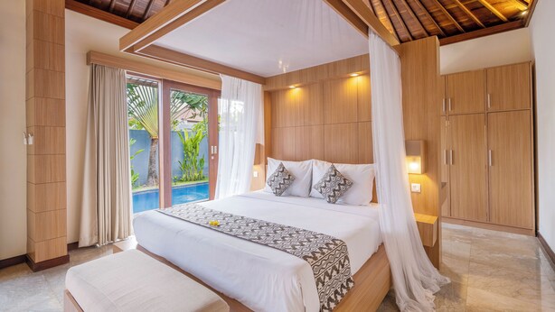 Un dormitorio amplio con una cama grande, un armario de madera y vistas a una piscina.