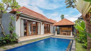 Una casa moderna con piscina, ventanas amplias y un patio.