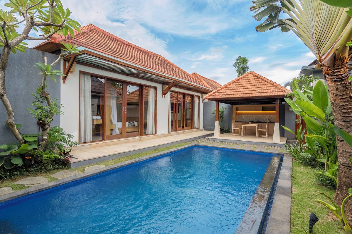 Una casa moderna con piscina, ventanas amplias y un patio.