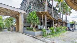 Un edificio moderno con un área exterior cubierta, una entrada pavimentada y una motocicleta estacionada cerca.