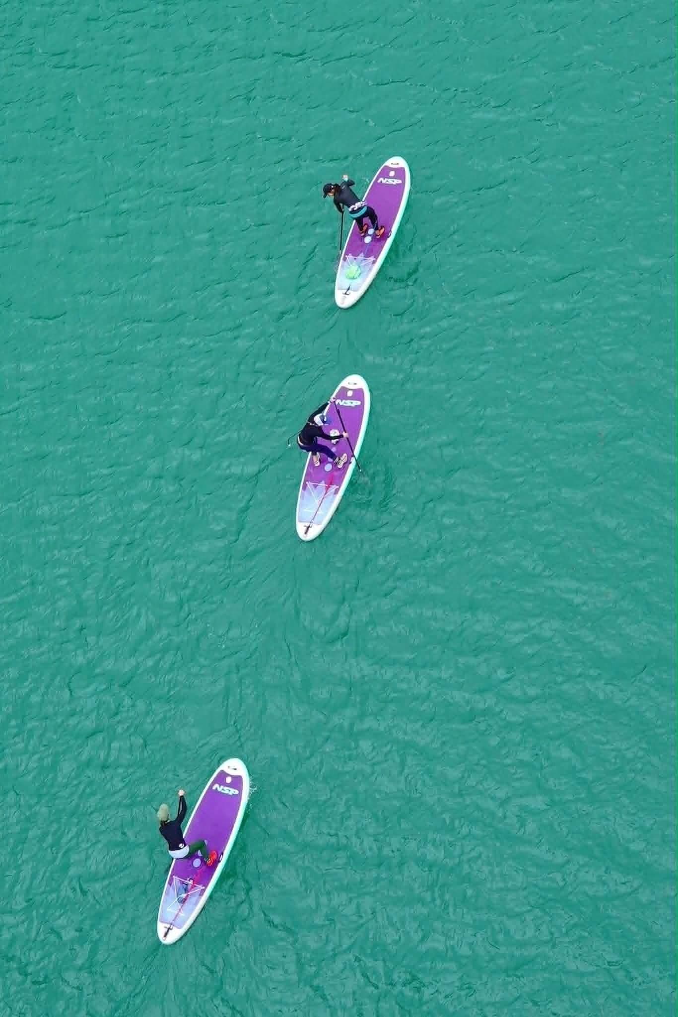 Three paddleboards on turquoise water.