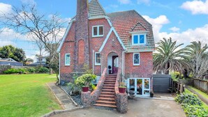 A brick house with a chimney, a front porch, and a staircase leading to the entrance.