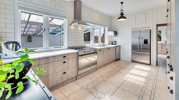 A modern kitchen with white brick walls, a central island, stainless steel appliances, and pendant lighting.