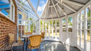 A sunroom with a brick exterior, large windows, and a table with chairs.