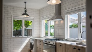 A modern kitchen with white brick walls, a large window, a built-in oven, and a washing machine.