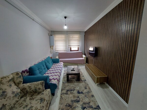 Una sala de estar con un sofá, una mesa de centro y un televisor montado en la pared.
