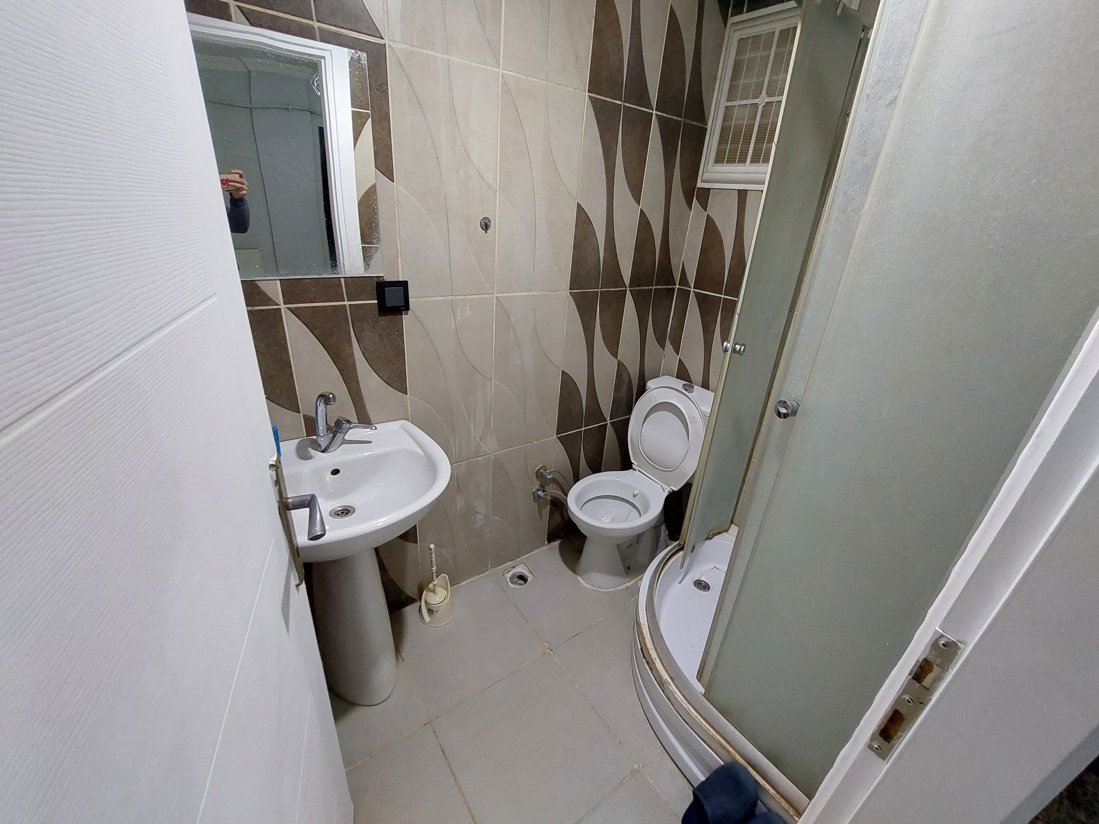 A compact bathroom with a sink, toilet, and shower area.