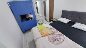 Un dormitorio con una cama, un armario azul, un espejo y una puerta.