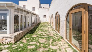 A courtyard with a stone pathway, white buildings, and arched windows. - 3787 ADT - Camera Matrimoniale Luxury (Mottola)